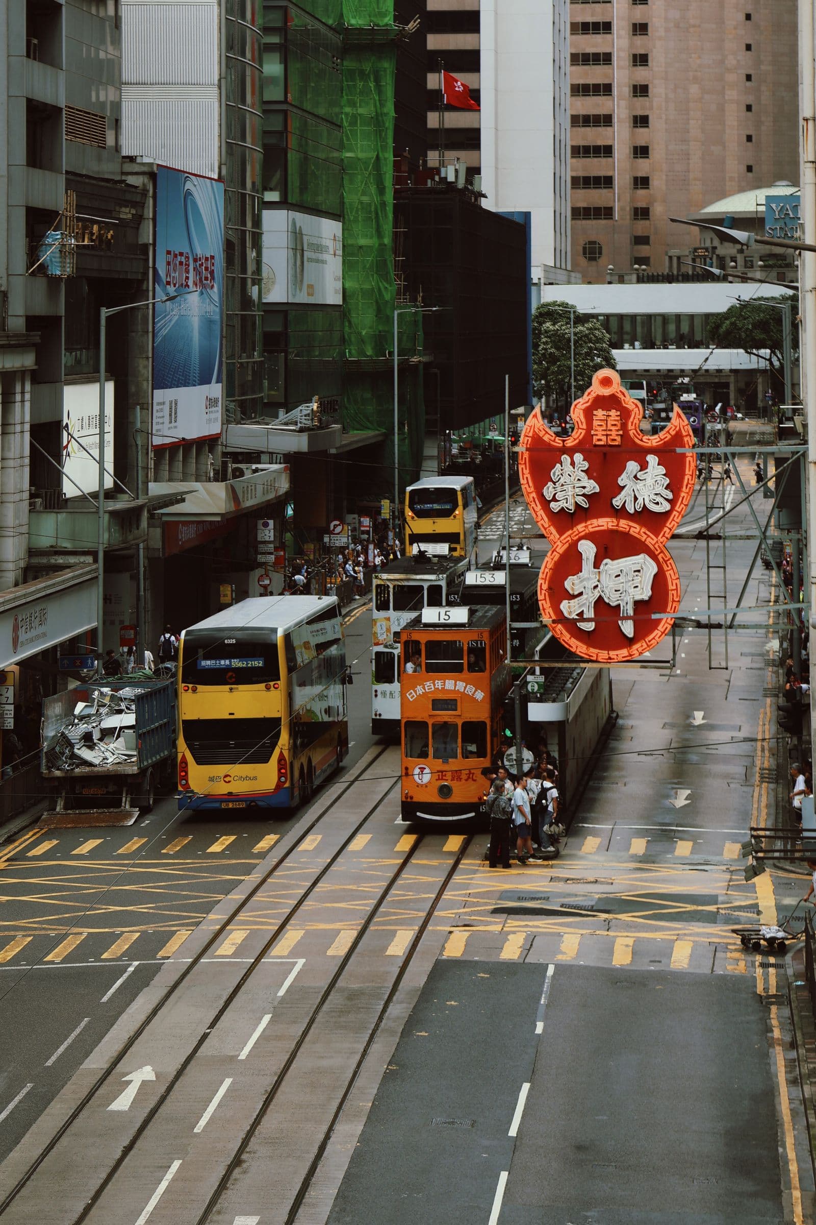 Trams and buses on a wet Hong Kong street beneath office towers